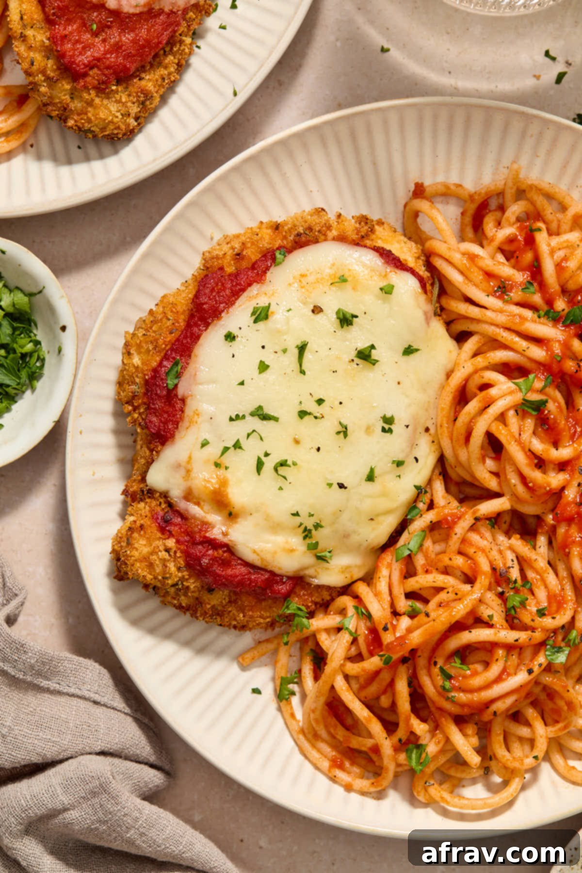 Close up of a piece of chicken parmesan on a plate with spaghetti noodles.