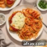 Air fryer chicken parmesan served on plates with spaghetti and marinara sauce.