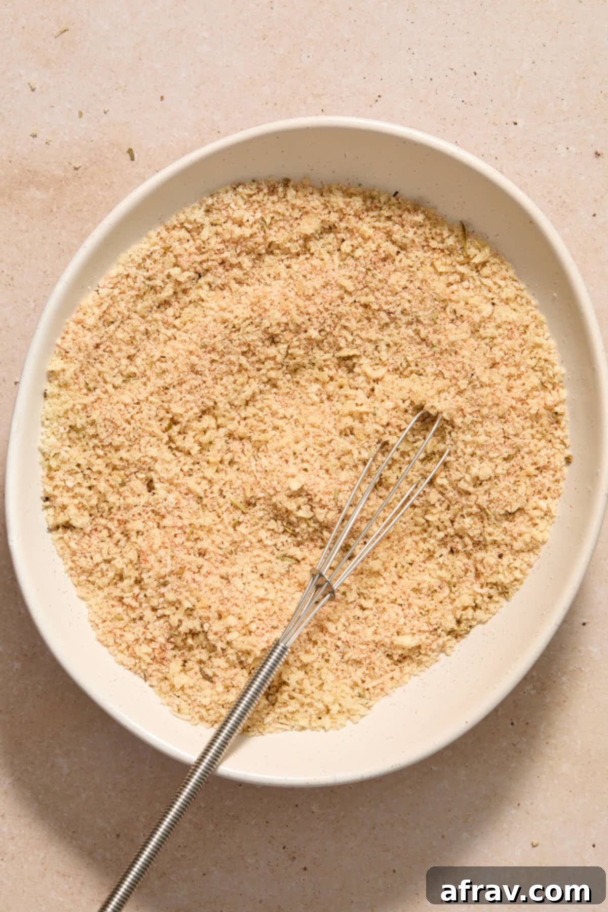 Panko crumbs, parmesan and seasonings whisked together in a shallow white bowl.