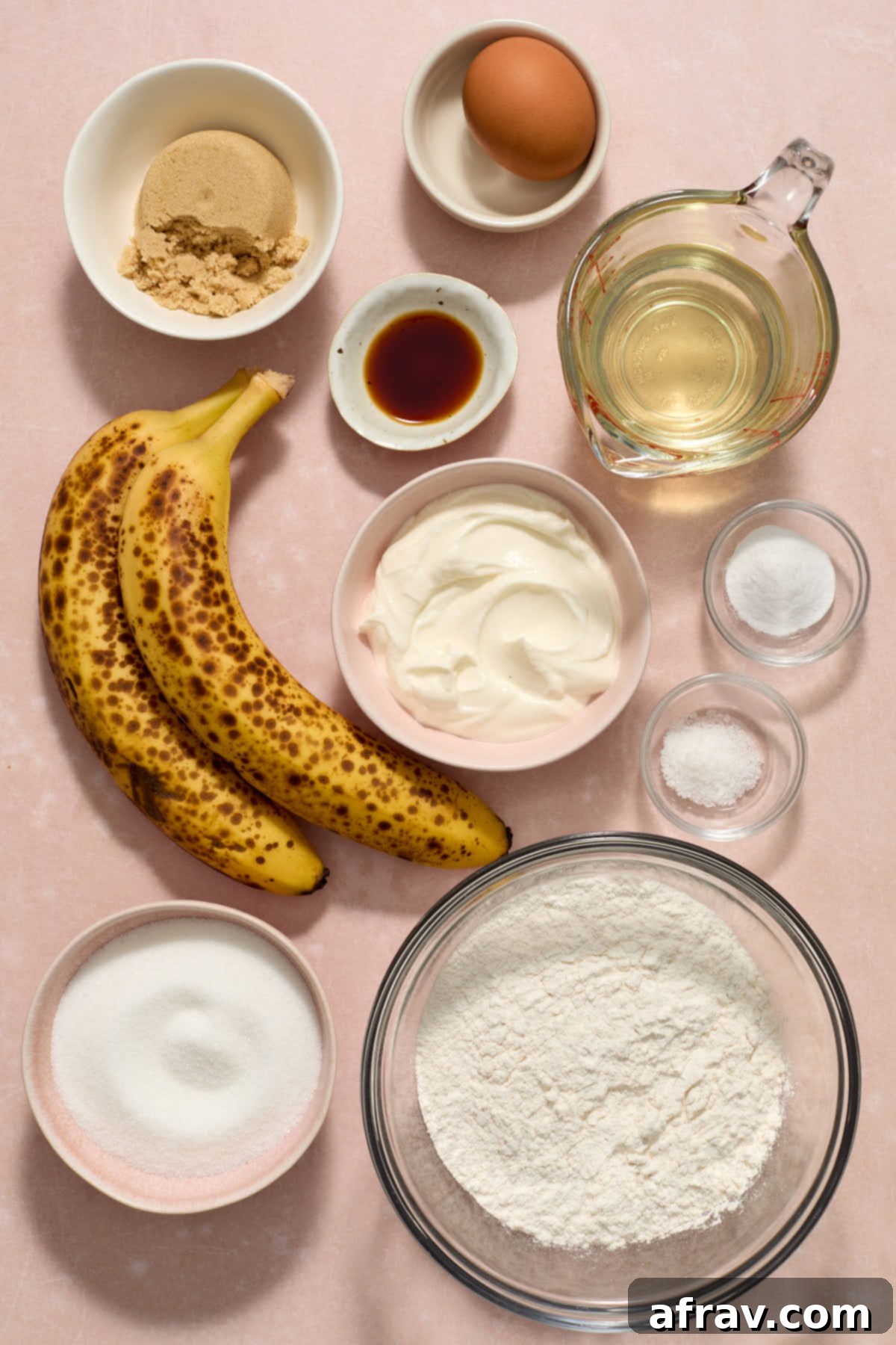 Double Sour Cream Banana Cake 3 A collection of ingredients for the sour cream banana cake, including very ripe bananas, flour, and sour cream, arranged on a pink surface.