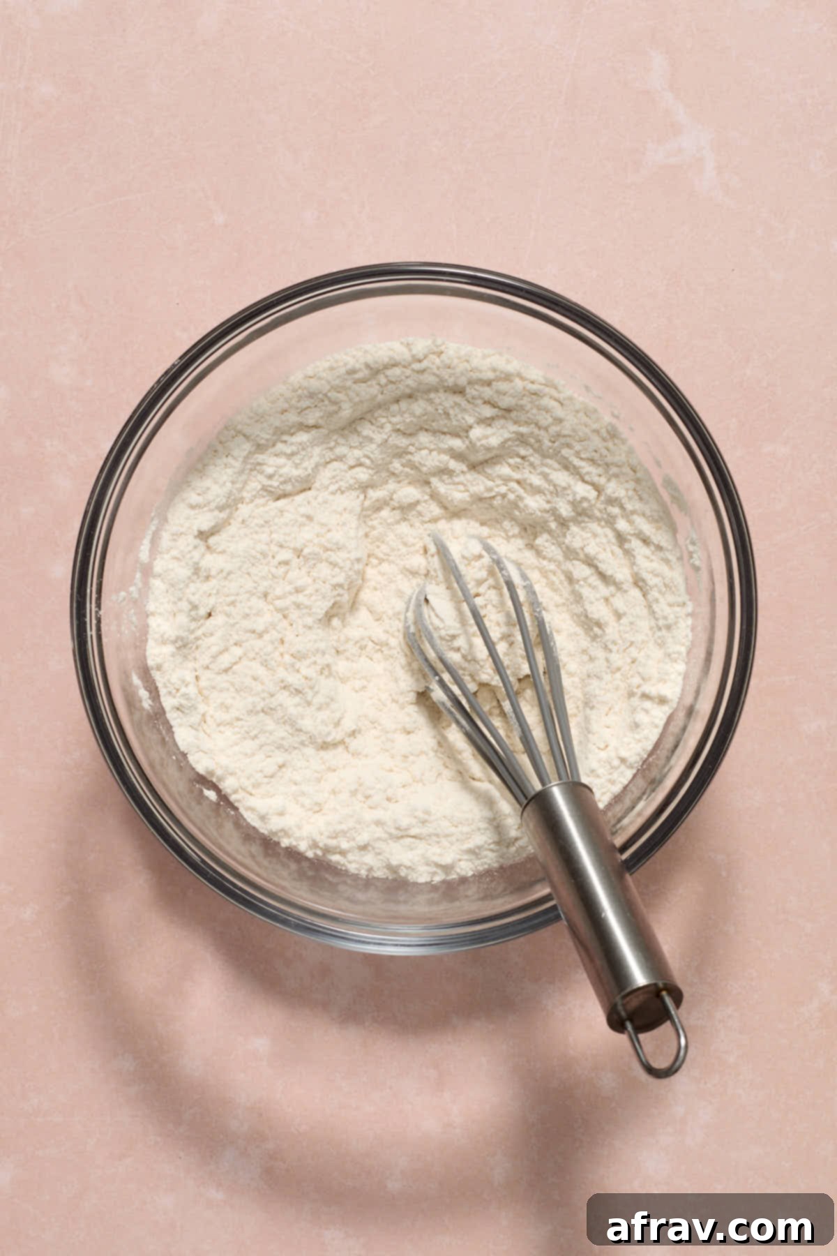 Double Sour Cream Banana Cake 5 Dry ingredients, including flour, baking soda, and salt, perfectly whisked together in a clear glass bowl, ready for combining.