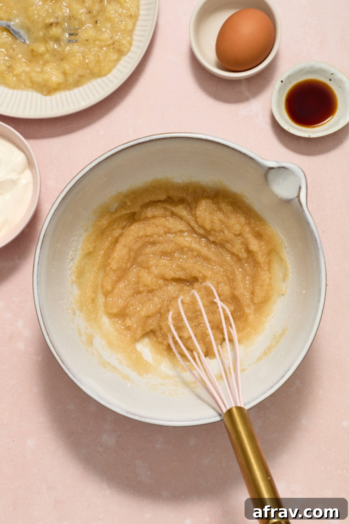 Double Sour Cream Banana Cake 6 Granulated sugar, brown sugar, and vegetable oil are expertly whisked until thoroughly combined in a pristine white mixing bowl.