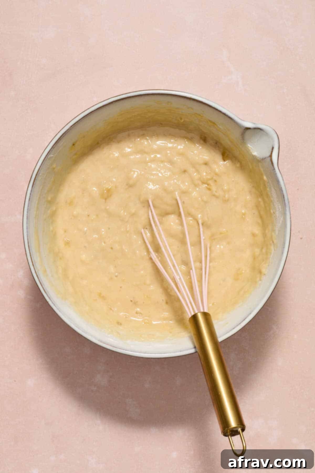Double Sour Cream Banana Cake 8 The dry flour mixture has been added to the wet ingredients and is being gently stirred, showing a lumpy but well-combined batter, indicating careful mixing.