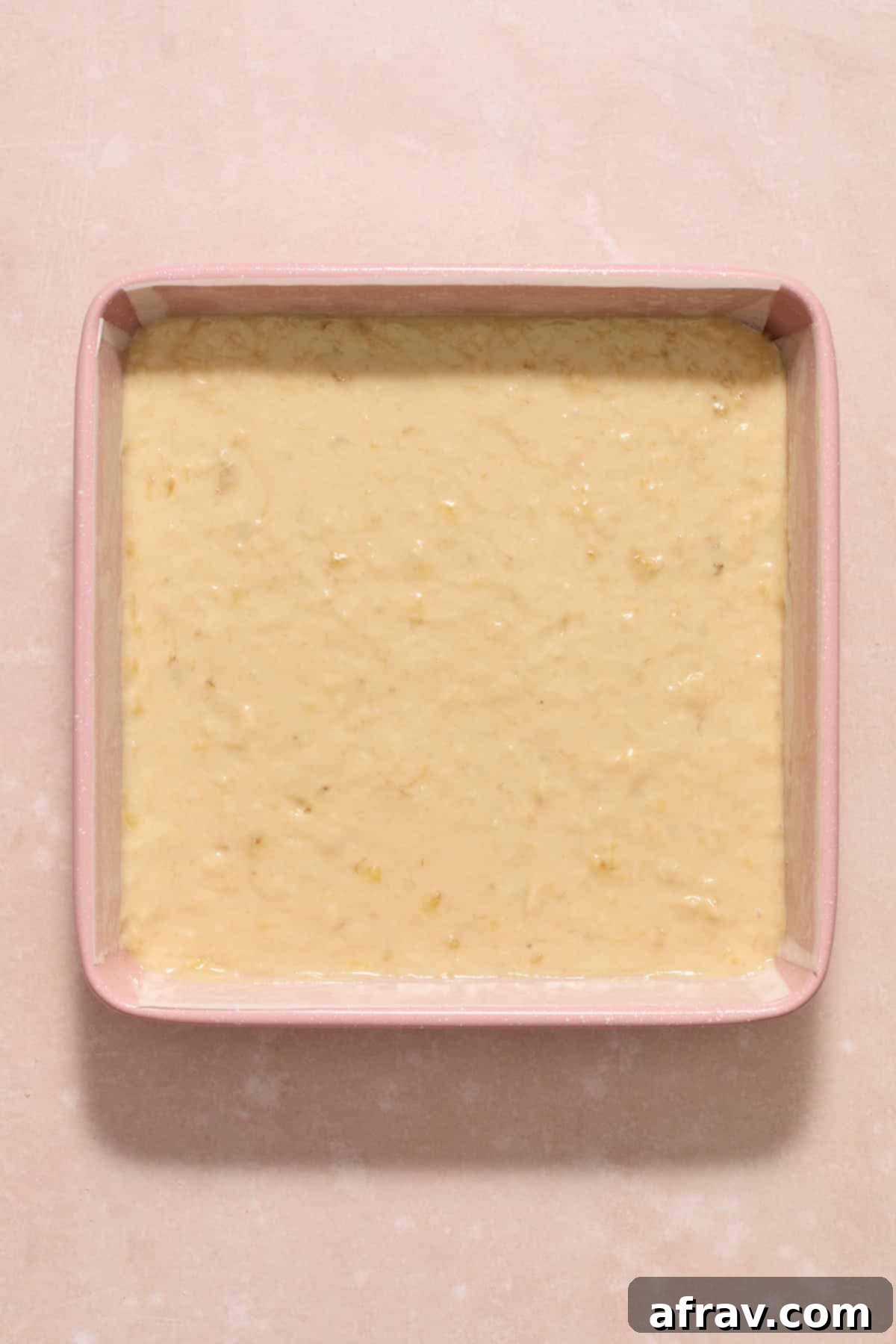 Double Sour Cream Banana Cake 9 Smooth banana cake batter evenly spread within a parchment-lined 9-inch square cake pan, ready for baking.