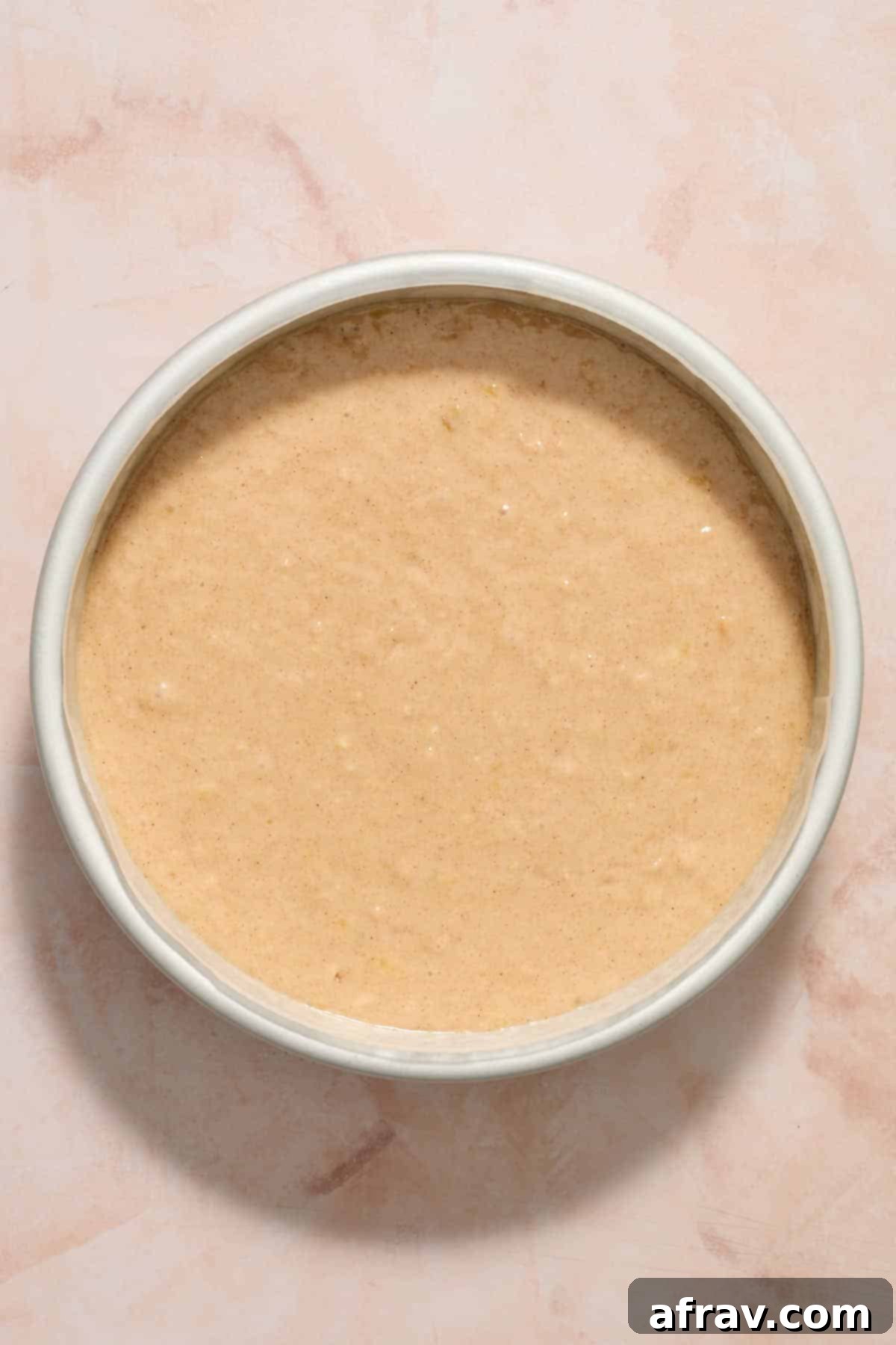 Cake batter in the parchment lined round cake pan.