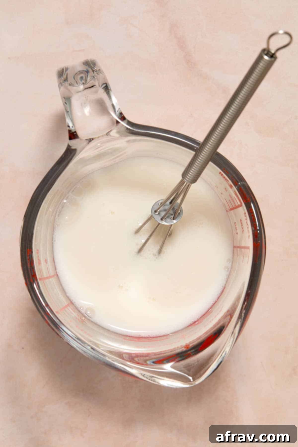 Milk and vinegar whisked together in a measuring cup.