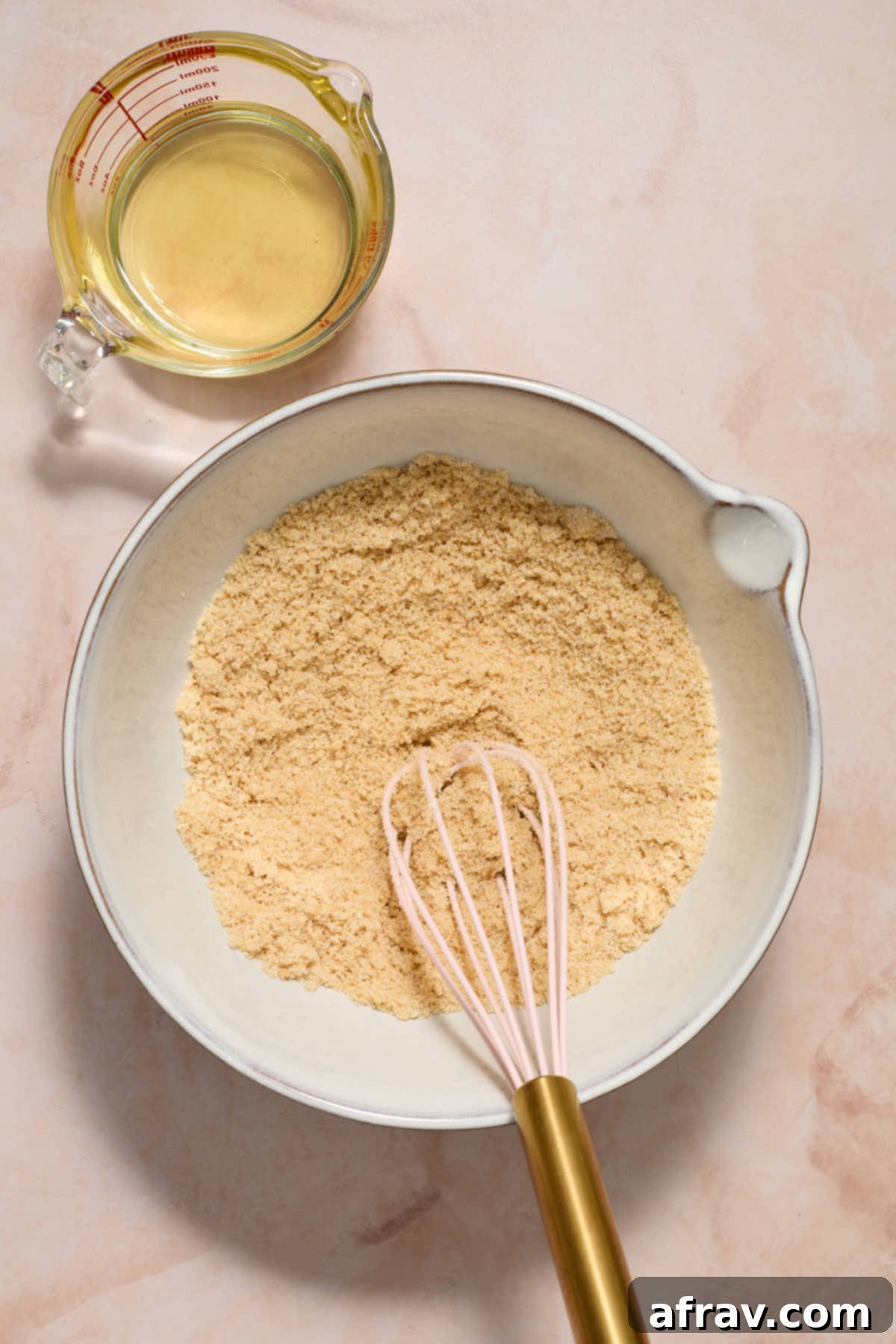 Sugars mixed together in a white bowl with a whisk and oil on the side.