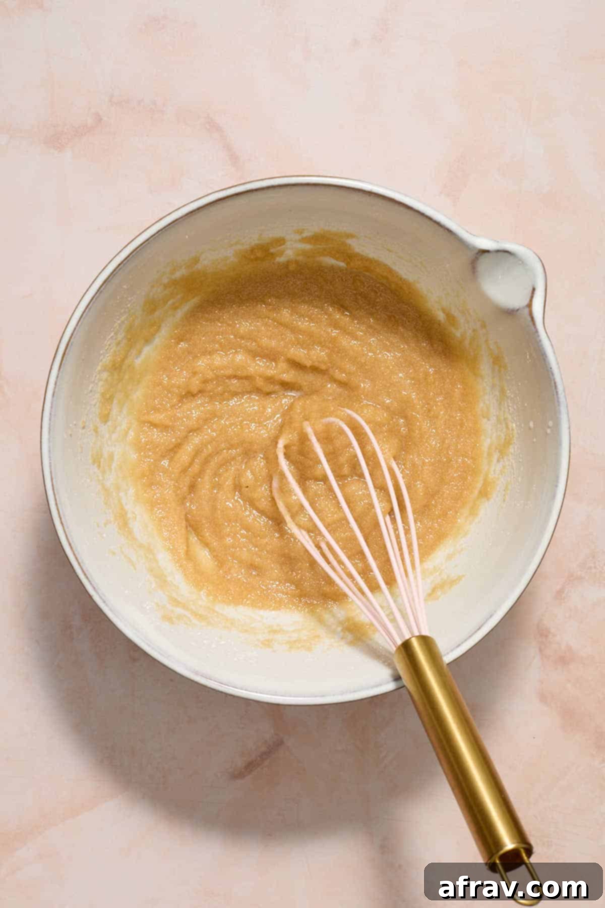 Sugars and oil whisked together in a white bowl.
