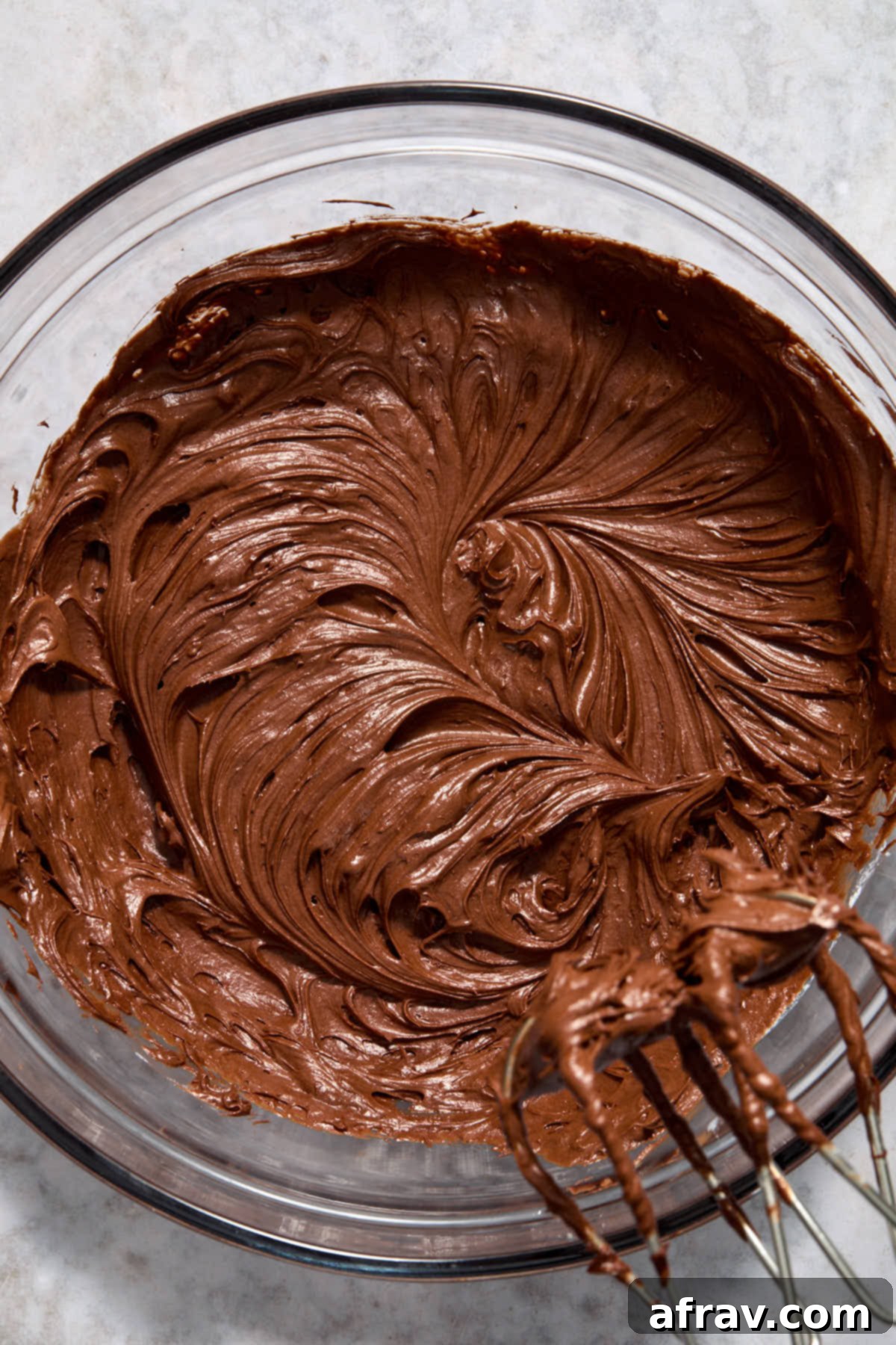 The chocolate sour cream frosting after being fully whipped, showing its smooth, creamy, and lightened texture in a glass bowl.