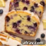 Slices of almond flour lemon blueberry bread topped with glaze and arranged on white parchment paper.