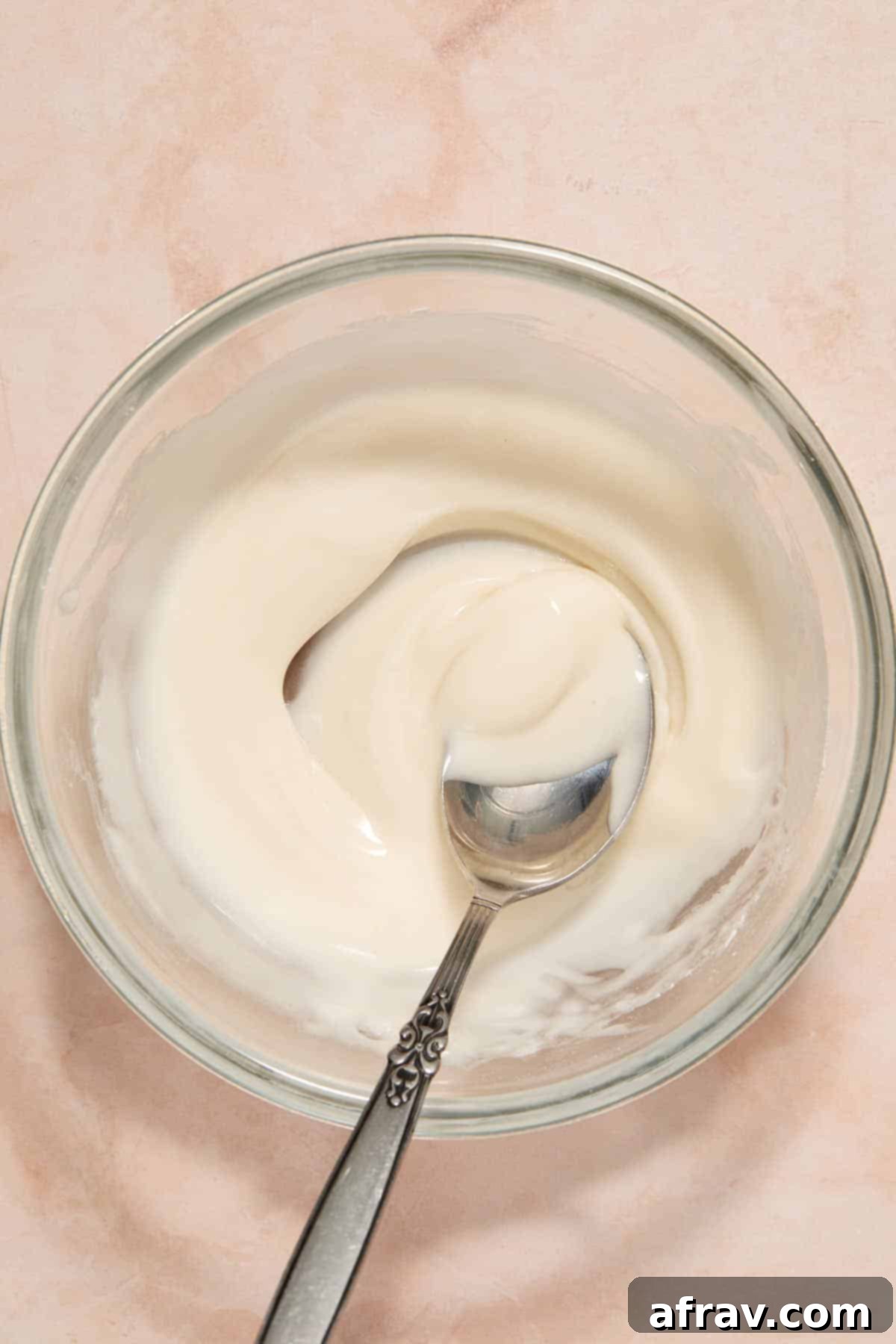 Powdered sugar glaze stirred together in a small bowl with a spoon.