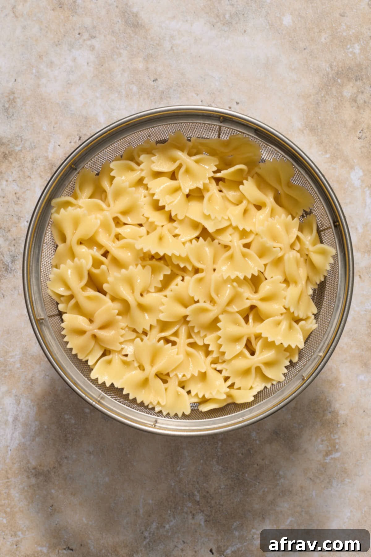 Perfectly cooked al dente bow tie pasta draining in a colander.