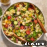 Italian bow tie pasta salad in a large bowl with wooden salad servers.