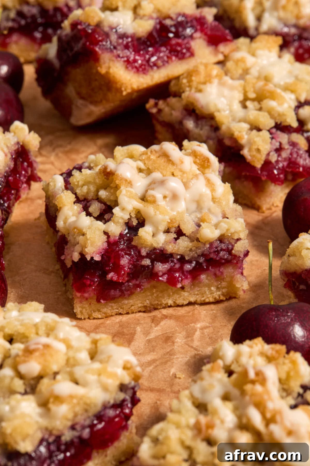 Side view of cherry bars on a sheet of brown parchment, showcasing the layers.