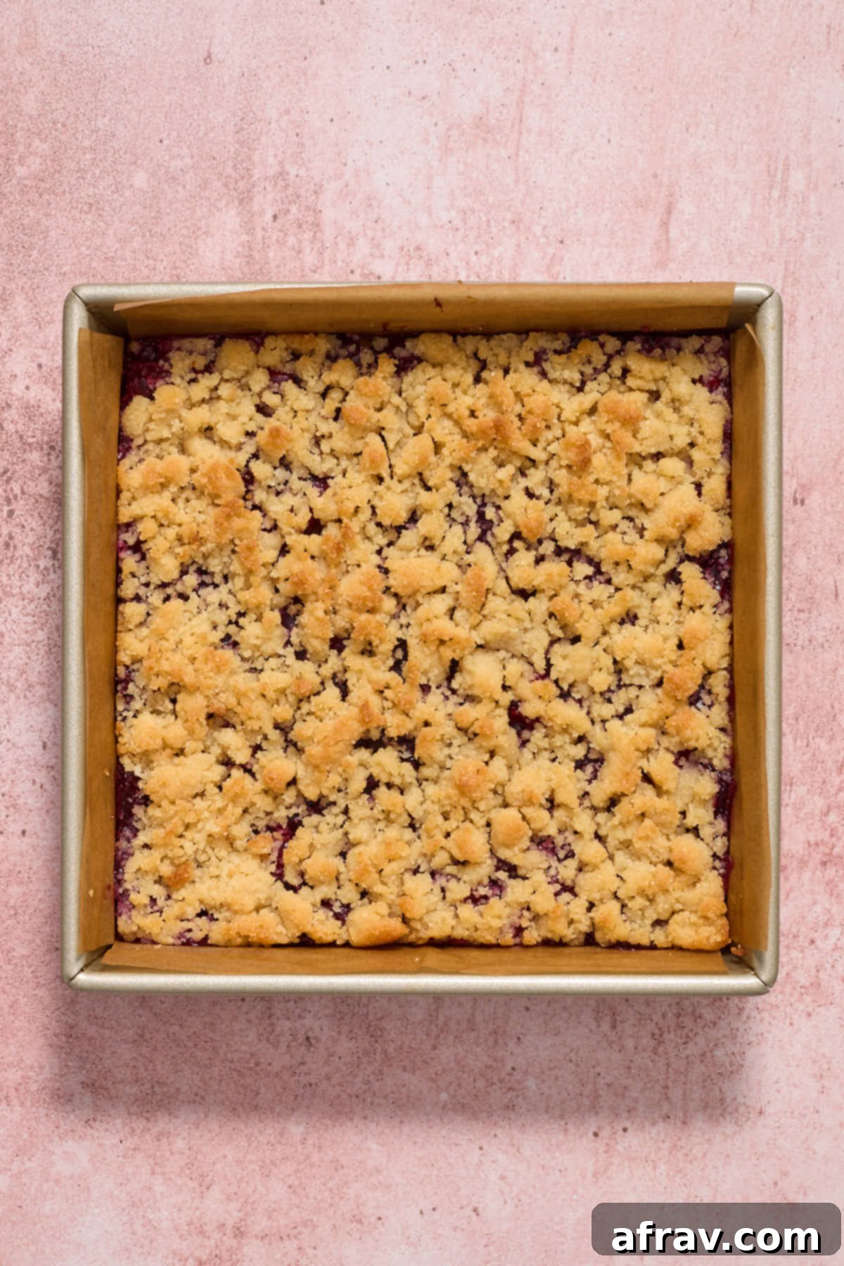 Baked cherry bars cooling in the pan, with a golden-brown topping.