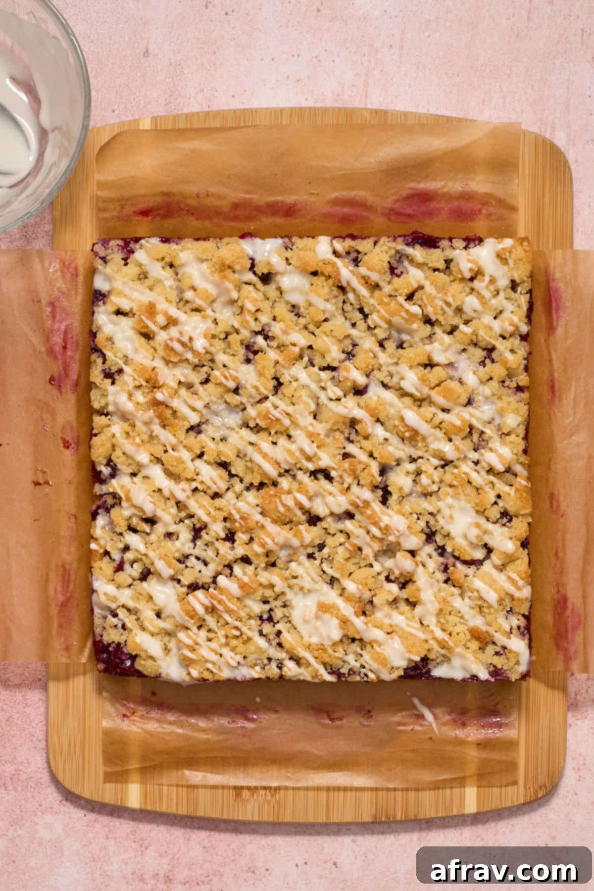 Chilled cherry bars on a wooden board with powdered sugar glaze elegantly drizzled over top.