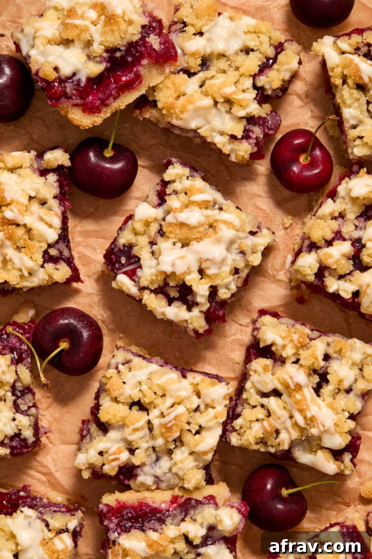 Overhead view of several cherry pie bars neatly arranged on brown parchment paper.