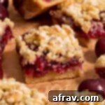 Close up side view of almond flour cherry pie bars arranged on brown parchment paper, showing layers.