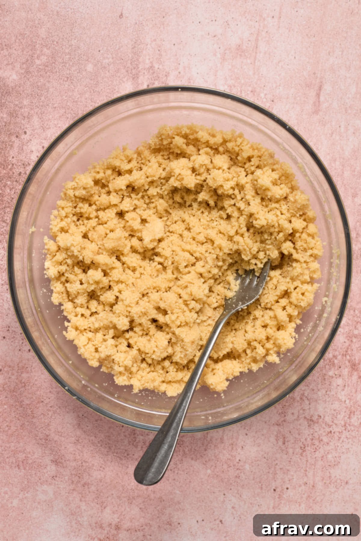 Crust and topping mixture in a glass bowl with a fork, showing the crumbly texture.