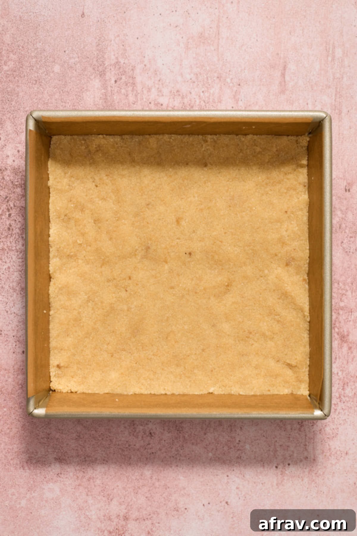 Crust mixture neatly pressed into the bottom of a square baking pan lined with parchment paper.