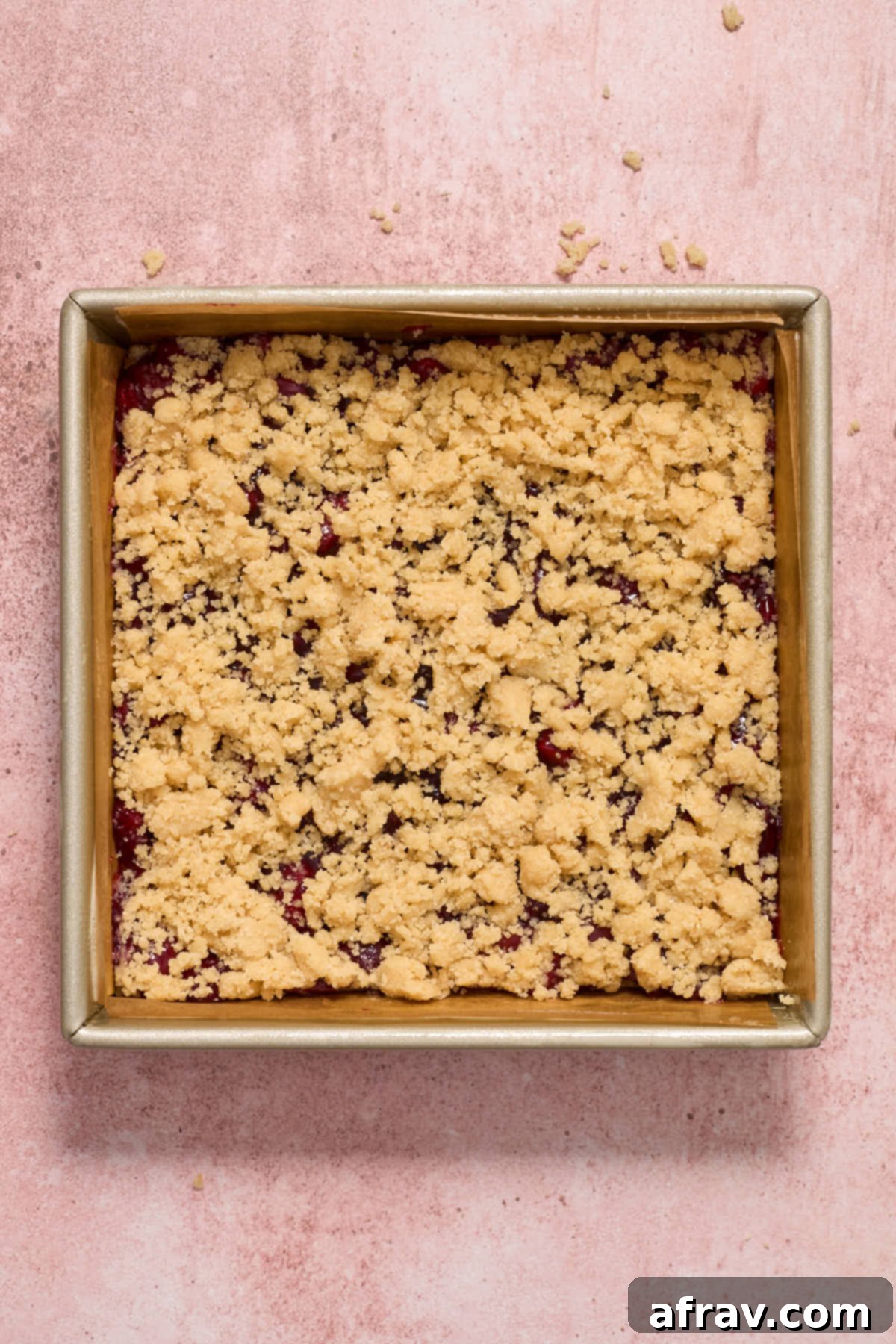 Crumbly topping sprinkled generously over the cherry filling layer.