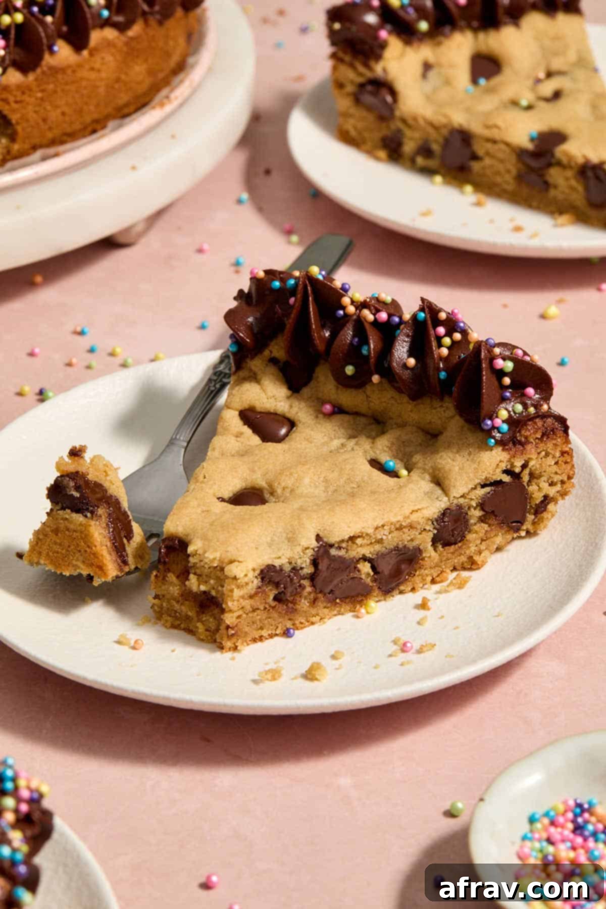 Slice of chocolate chip cookie cake on a white plate with a forkful removed.