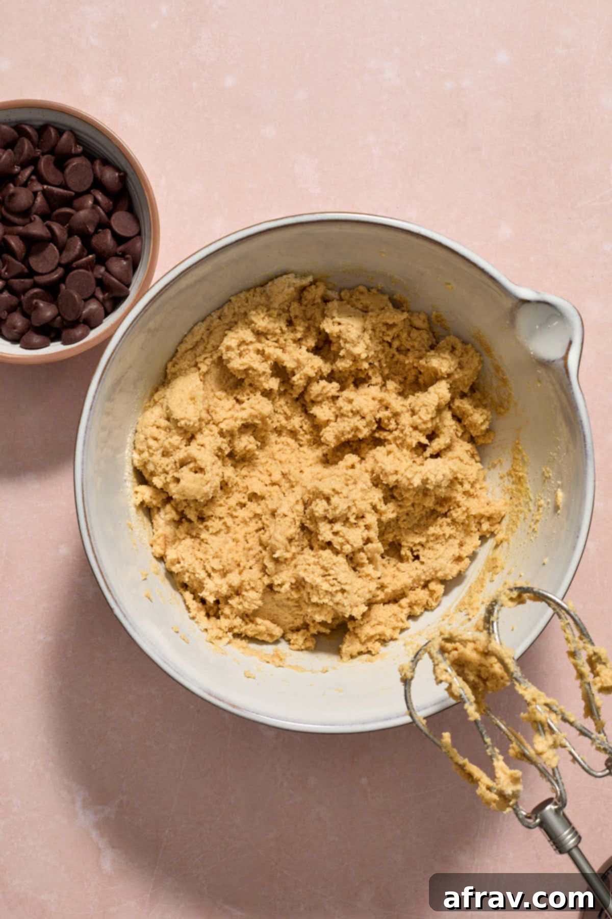 Cookie dough mixed together in a bowl with chocolate chips on the side.