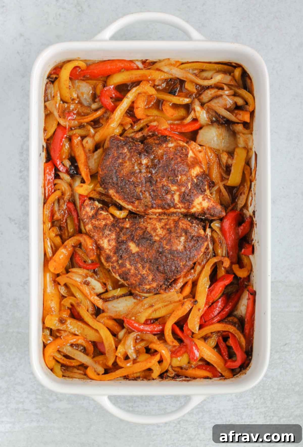 Sheet Pan Fajitas 5 A close-up of a baking dish filled with colorful bell peppers and onions, actively cooking in the oven, with steam rising.