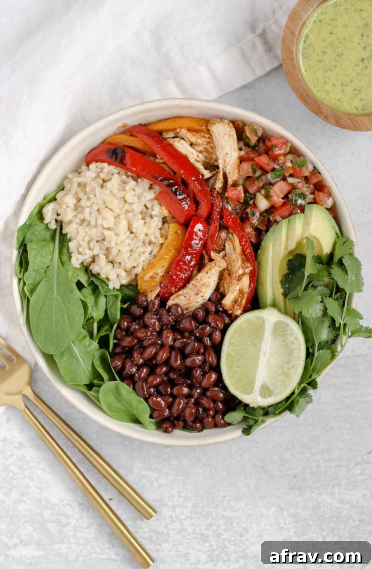 Sheet Pan Fajitas 7 A vibrant chicken fajita salad in a white salad bowl, accompanied by a small bowl of cilantro lime dressing, ready to be enjoyed.