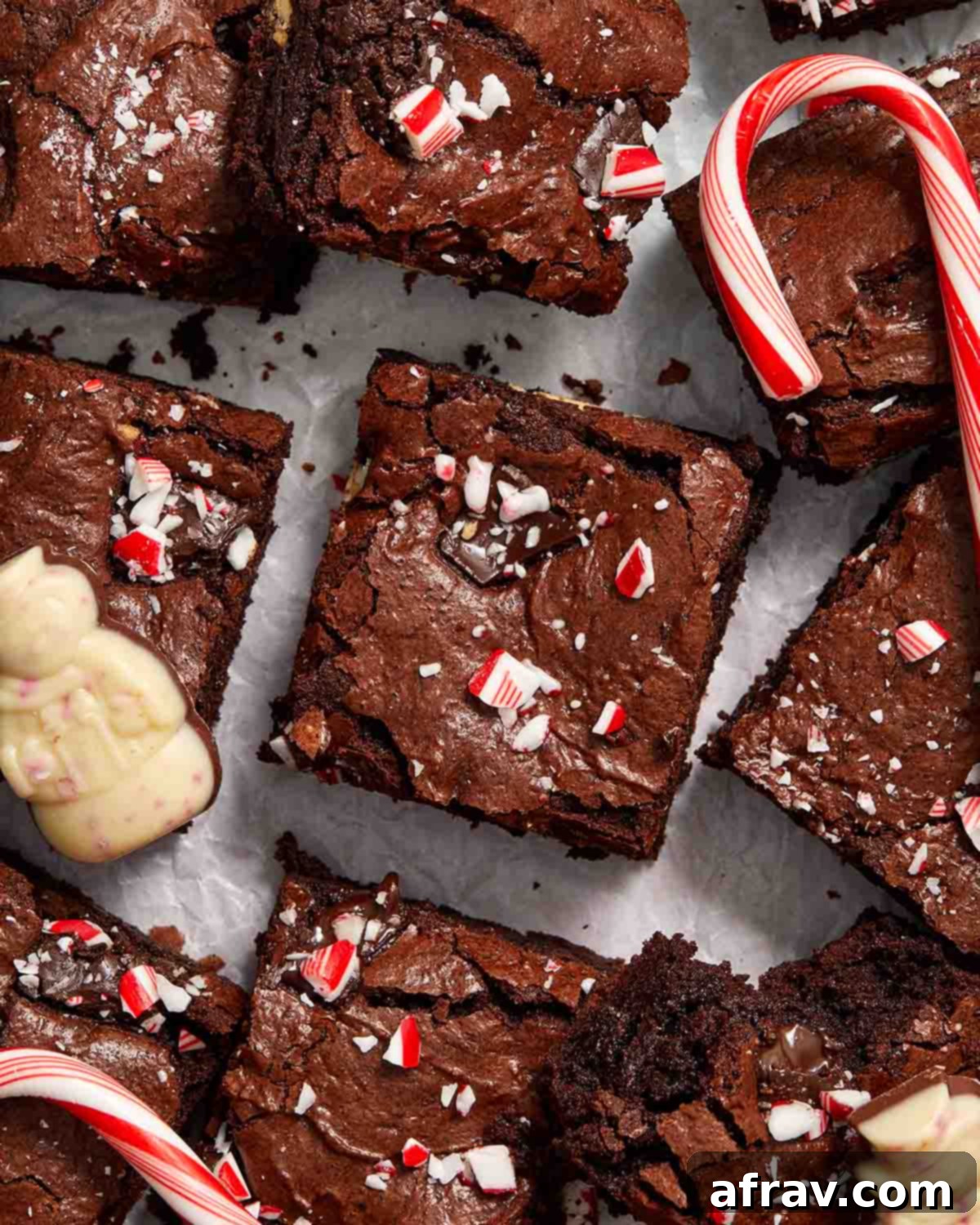 Minty Mocha Magic Brownies 11 Brownies arranged on parchment paper with candy canes and peppermint bark.