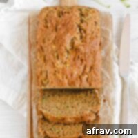loaf of zucchini bread half sliced on a cutting board