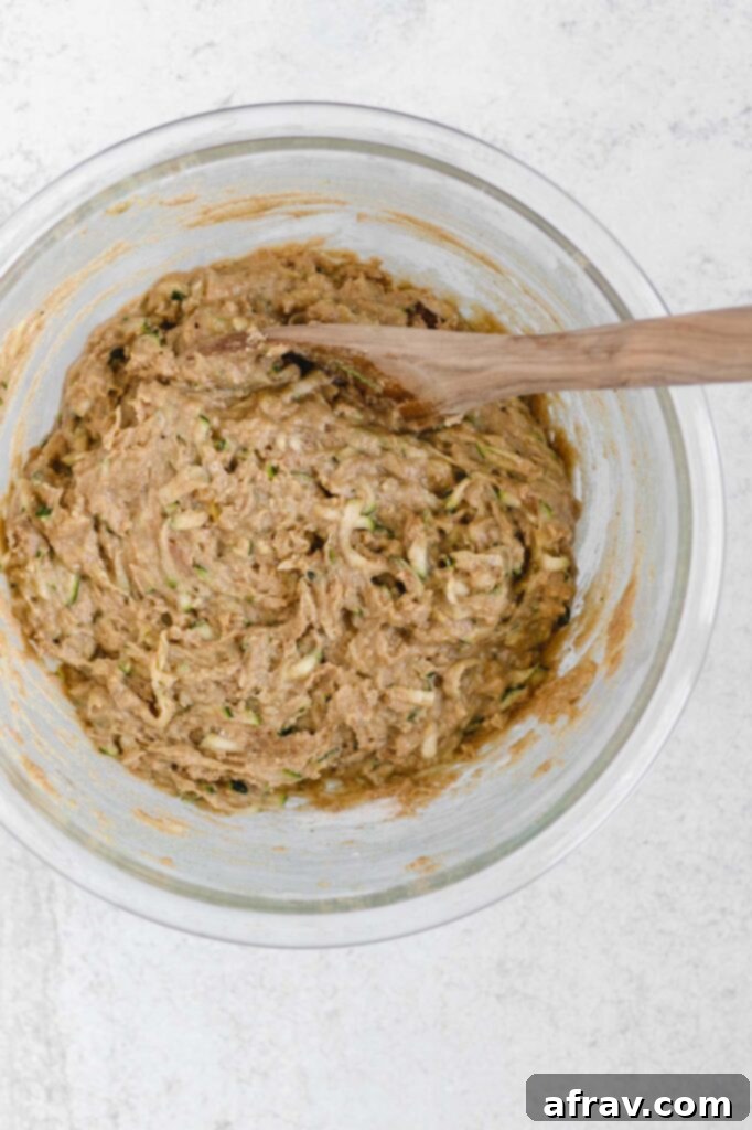 All zucchini bread ingredients mixed together in a glass bowl, creating a thick batter.