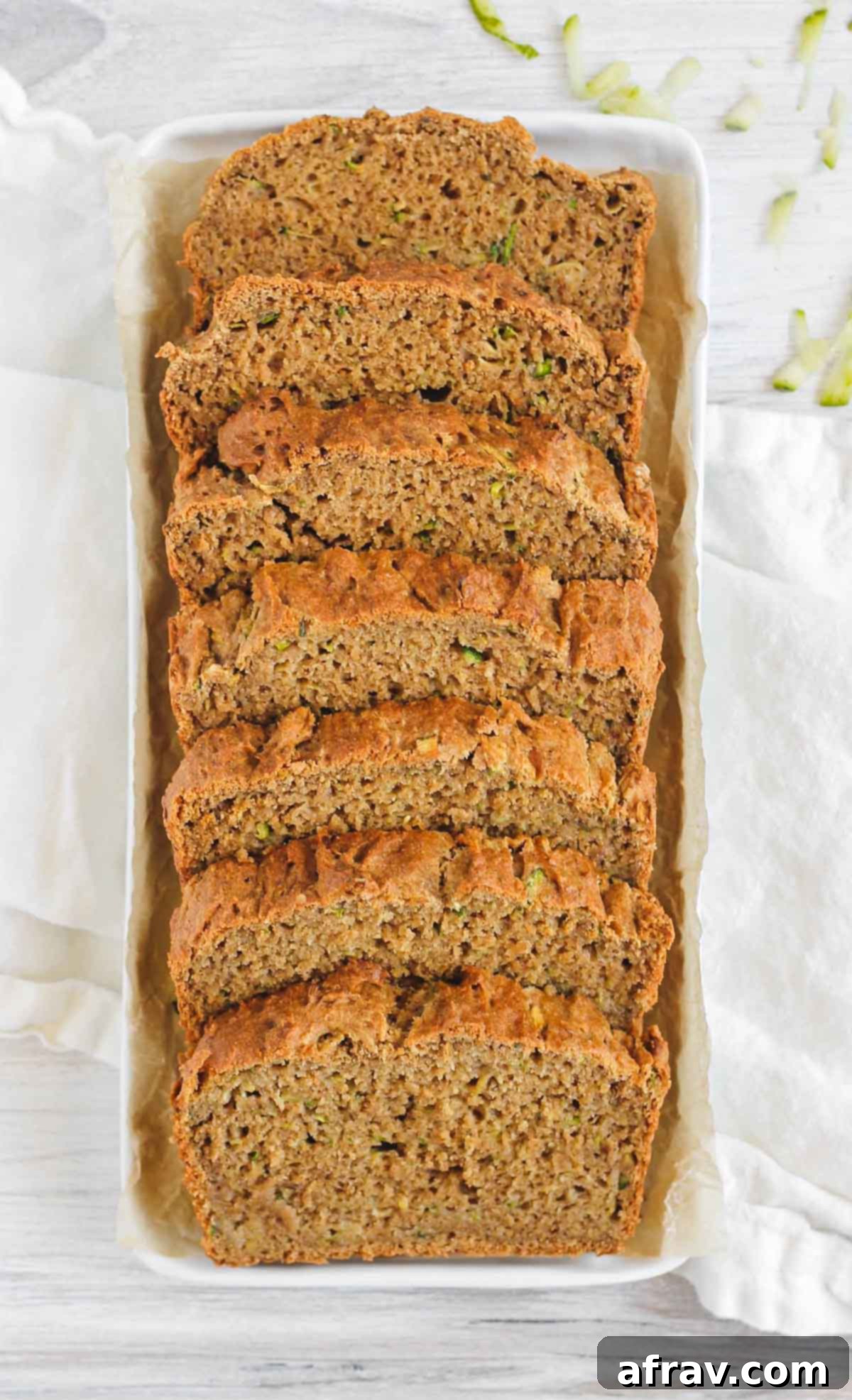 A long white plate holding several slices of gluten-free zucchini bread, ready to be served.