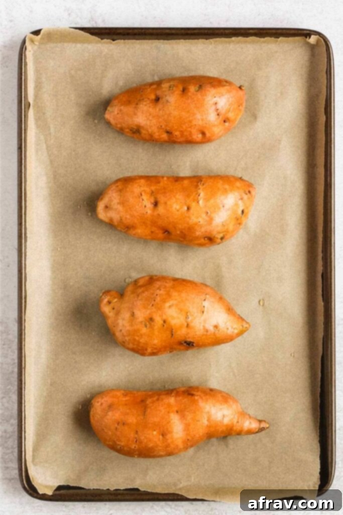 Raw whole sweet potatoes on a baking sheet.