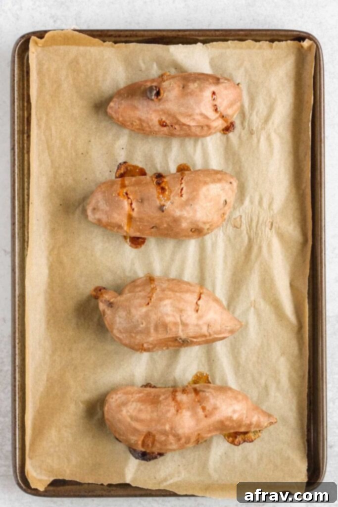 Cooked whole sweet potatoes on a baking sheet.