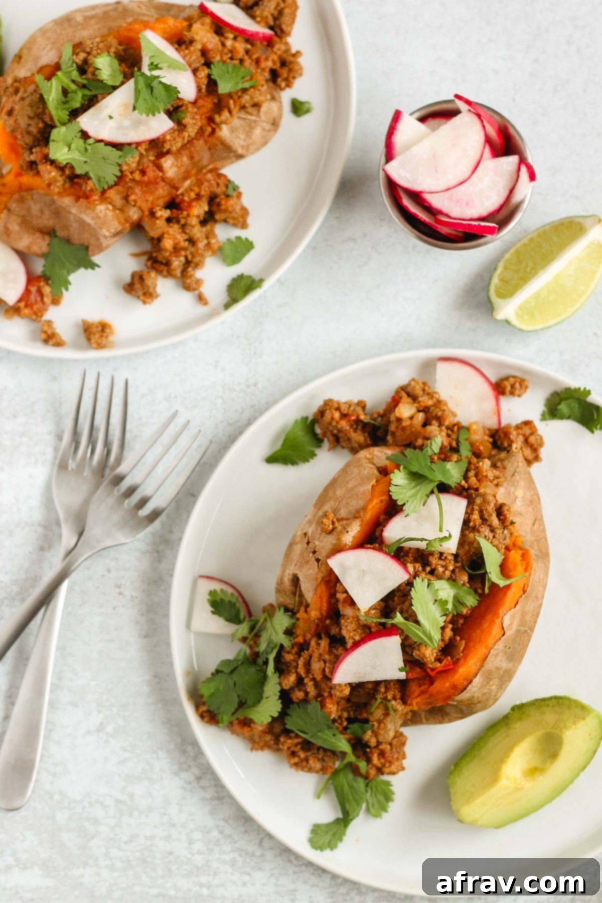 Two separate plates with one chili stuffed sweet potato on each plate.