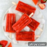 Simple 2-Ingredient Strawberry Watermelon Popsicles 6 strawberry watermelon popsicles on a round white plate with ice cubes