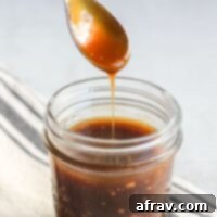 Teriyaki sauce dripping from a spoon over a mason jar filled with teriyaki.
