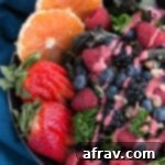 Berry Citrus Kale Salad with Raspberry Vinaigrette in a black bowl, ready for healthy meal prep.
