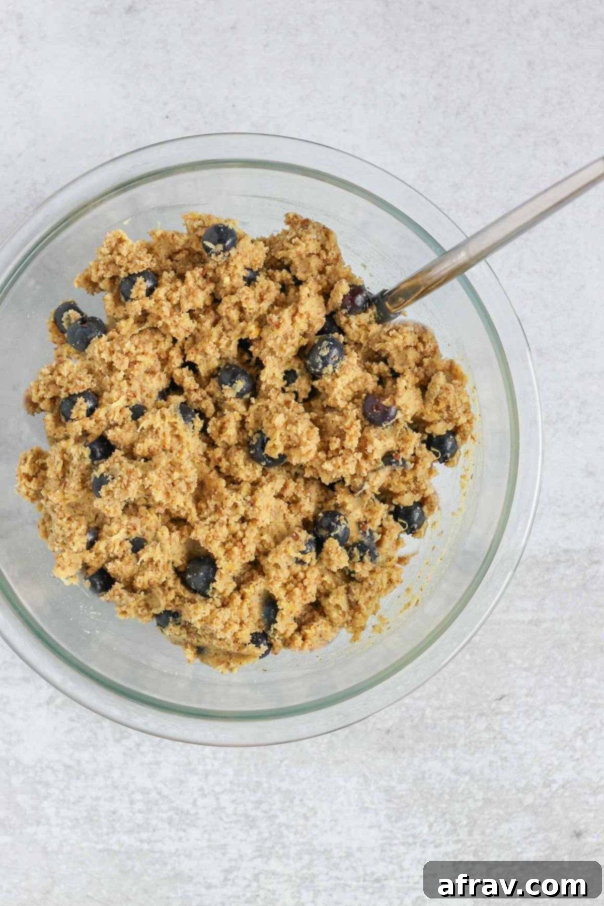 Zesty Lemon Blueberry Almond Loaf 6 Almond flour blueberry bread batter in a mixing bowl with a spatula, showing blueberries folded in.
