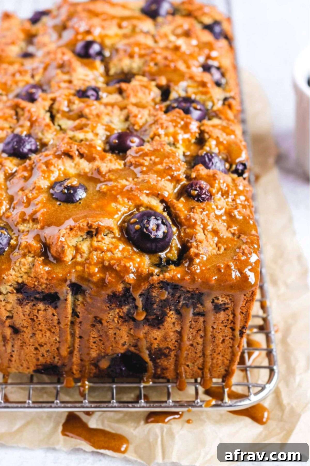 Zesty Lemon Blueberry Almond Loaf 9 Almond flour blueberry bread loaf drizzled with coconut sugar glaze on a cooling rack.