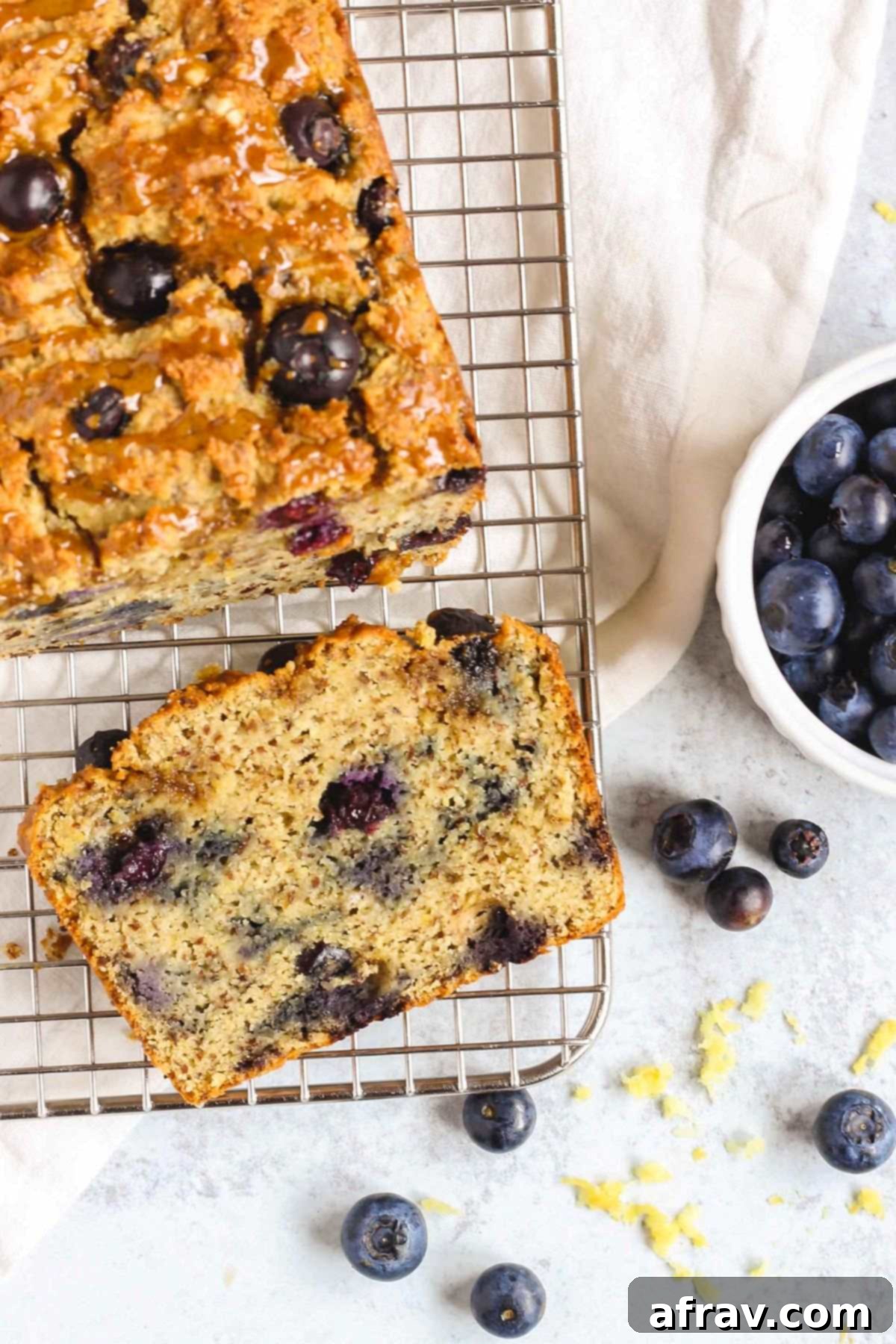 Zesty Lemon Blueberry Almond Loaf 10 Blueberry lemon almond flour bread with one slice cut from the loaf on a wire cooling rack, ready to eat.