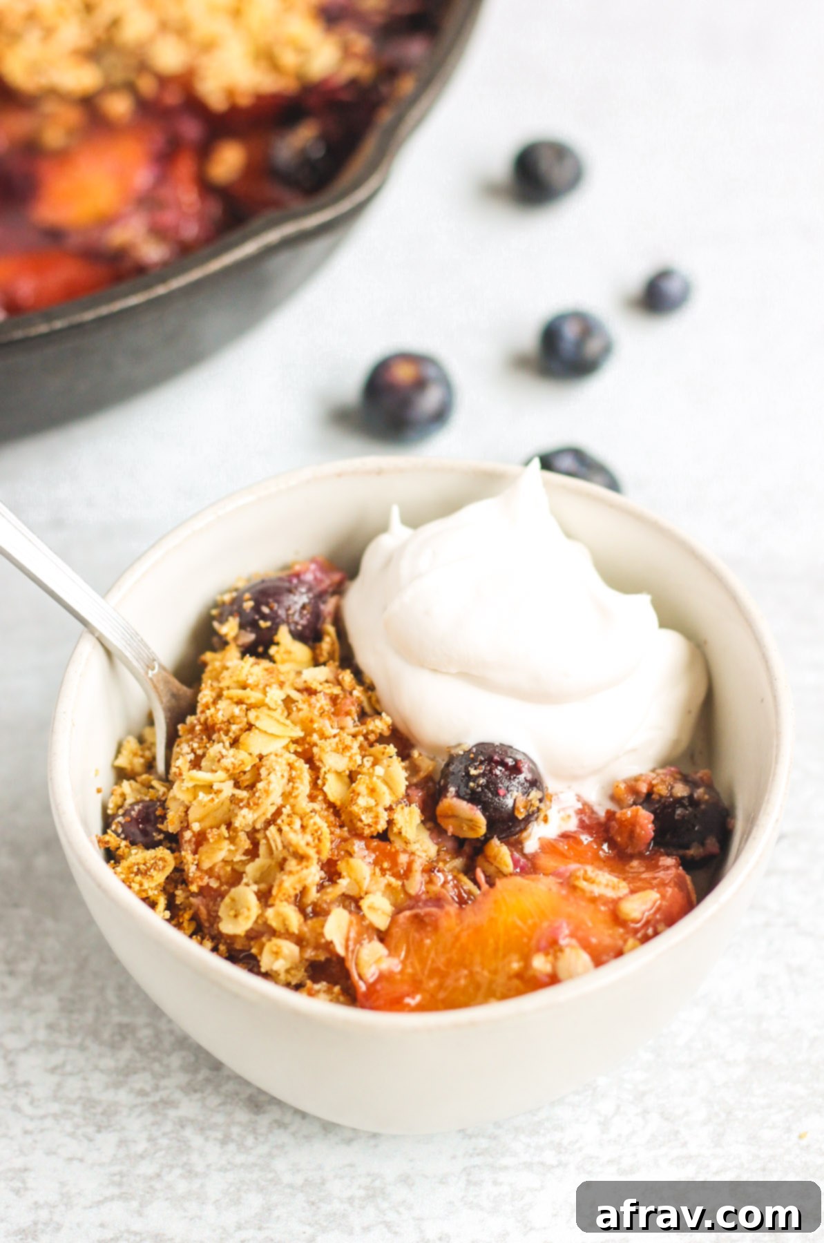 peach crisp in small serving bowl topped with coconut whipped cream