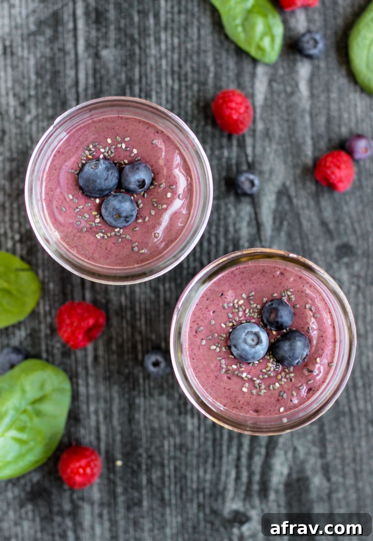 Plant-Based Berry Spinach Smoothie 2 overhead view of two smoothies topped with blueberries with berries and spinach sprinkled on the surface
