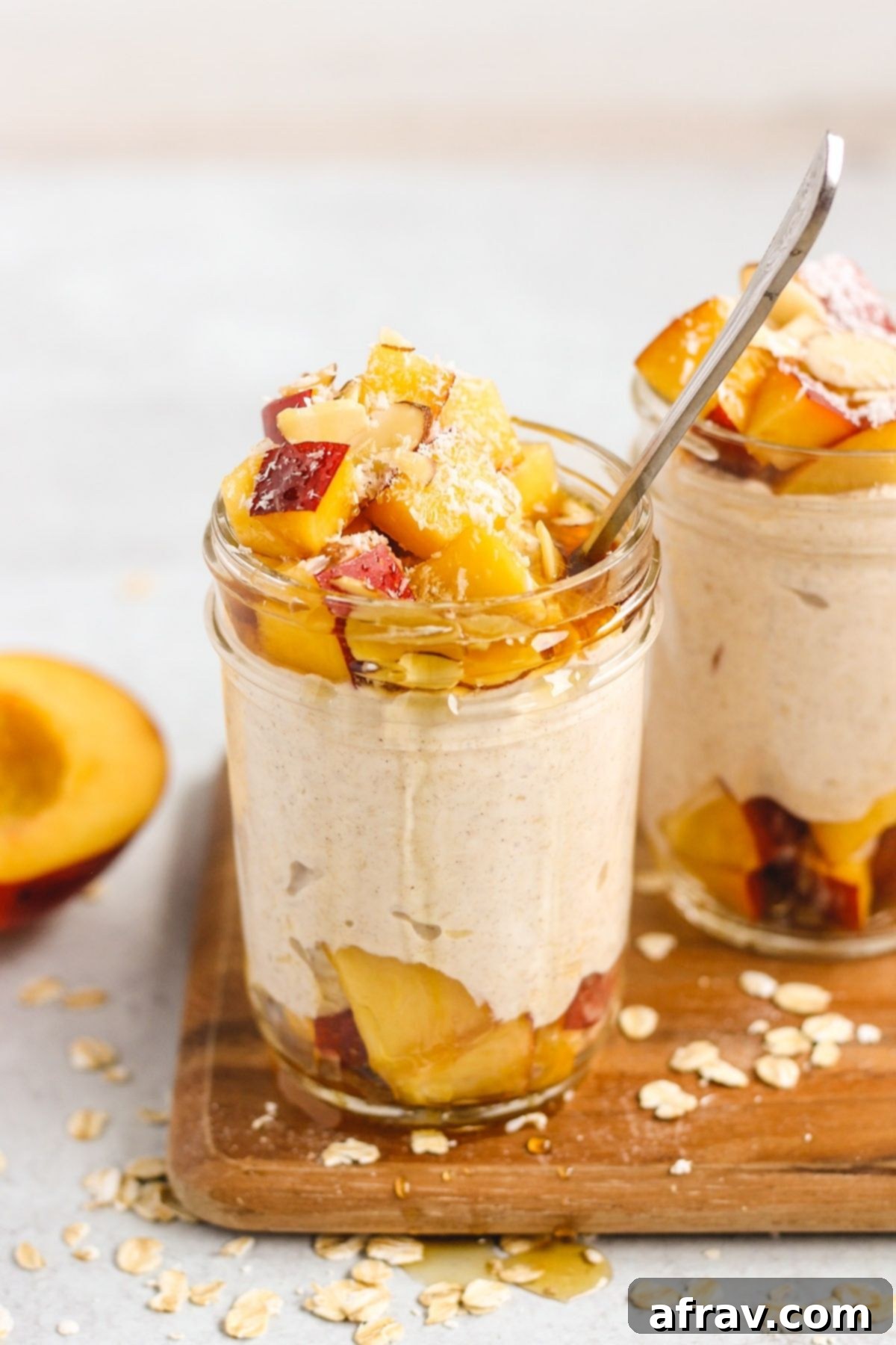 Peaches and cream overnight oats dripping with syrup in a mason jar with a spoon.