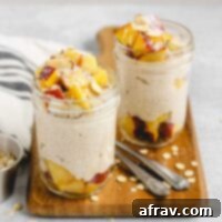 Two mason jars on a wood cutting board filled with overnight oats topped with peaches, almonds, and coconut. Oats sprinkled on the cutting board.