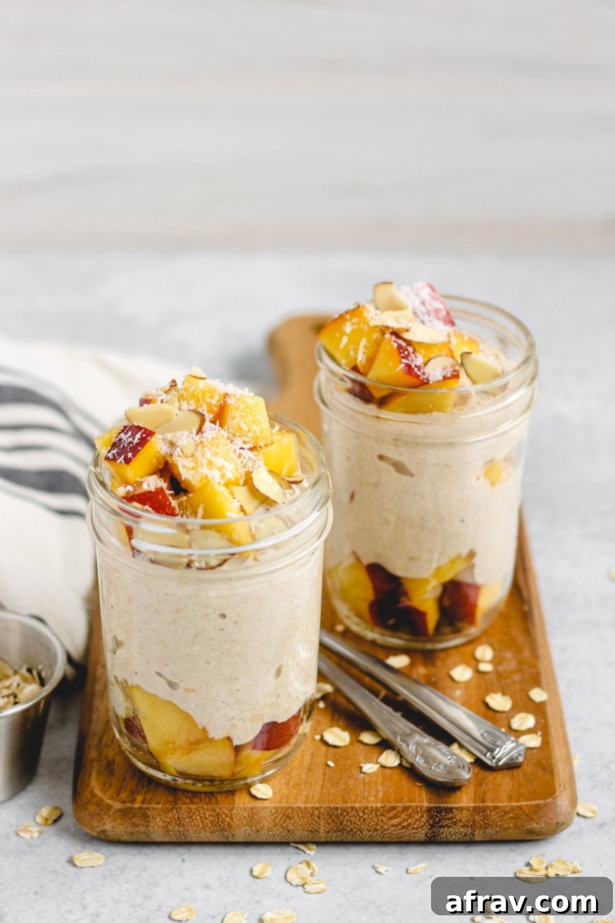 Two mason jars filled with overnight oats topped with peaches and coconut.