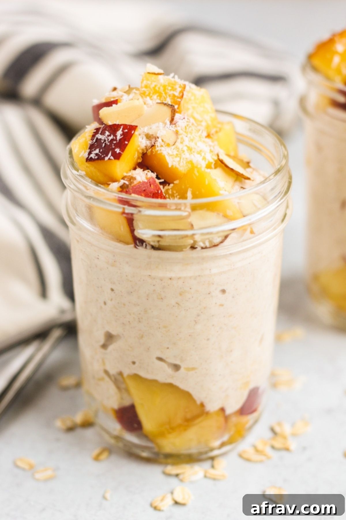 Mason jar filled with overnight oats topped with peaches and almond slices.