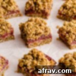 Strawberry Steel Cut Oat Bars 2 Strawberry oat bars arranged on parchment paper on a pink surface.