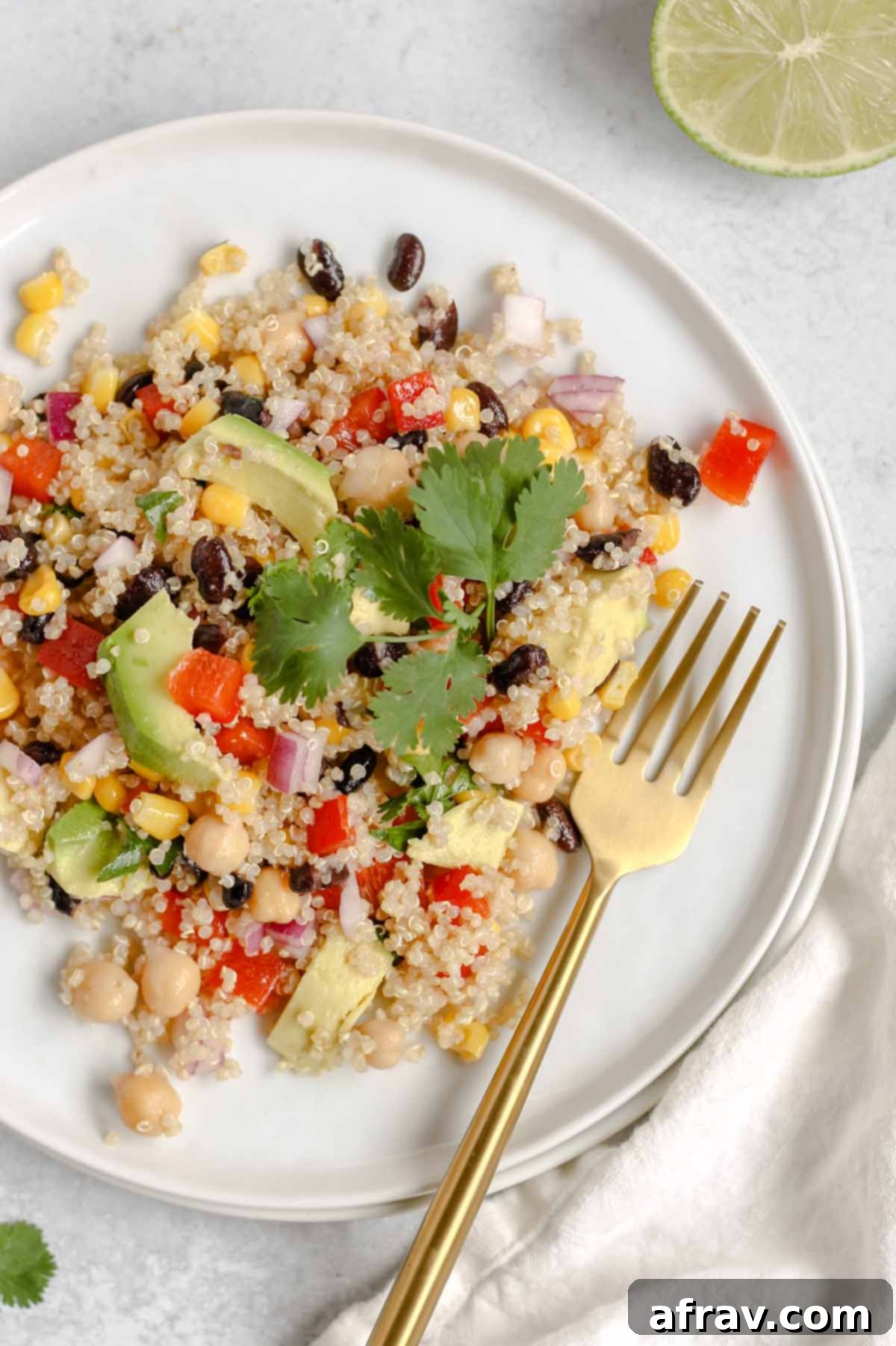 Single serving of southwest quinoa salad on a small white plate, showcasing the colorful ingredients and a zesty lime wedge.